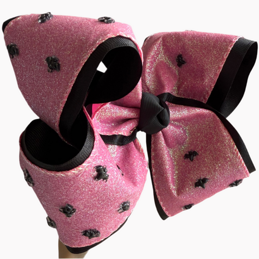 Pink glittery hair bow with black accents on a white background